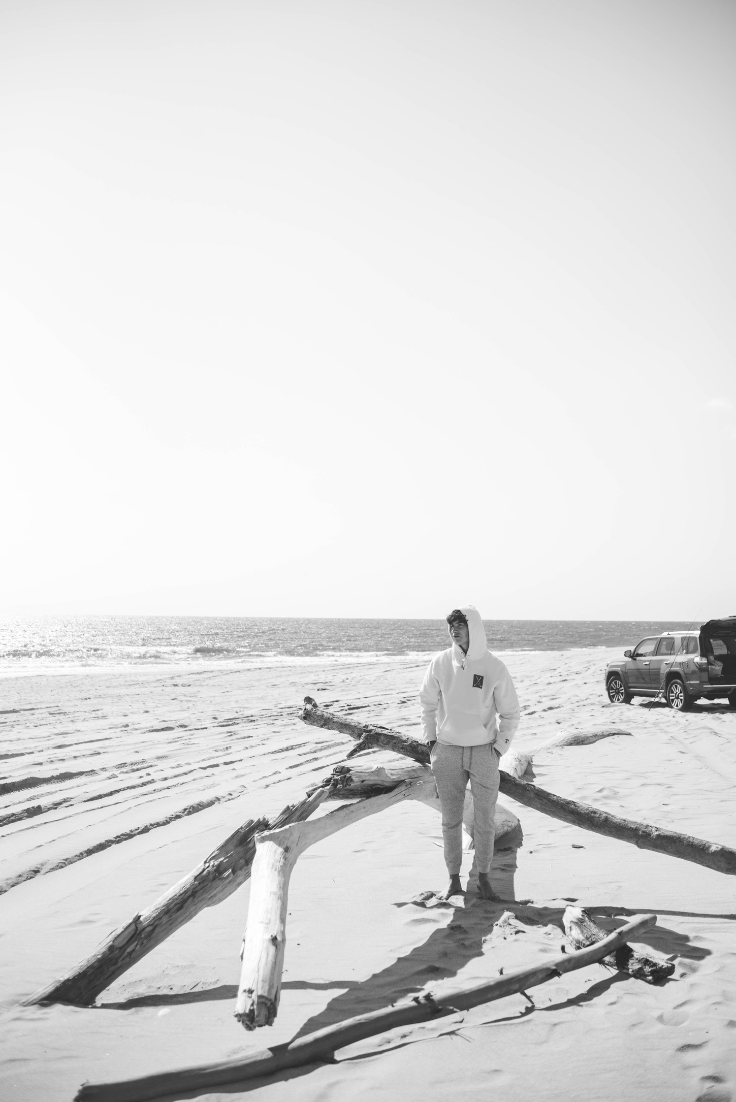 Ryan among driftwood on the beach, in black and white